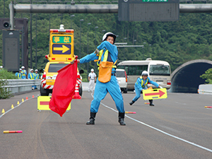 監視担当は通行車の誘導や後続のお客さまに異常をお知らせし、作業担当は監視担当の合図のもと作業を行います