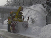 在公路旁的斜坡上拋雪的旋轉掃雪機